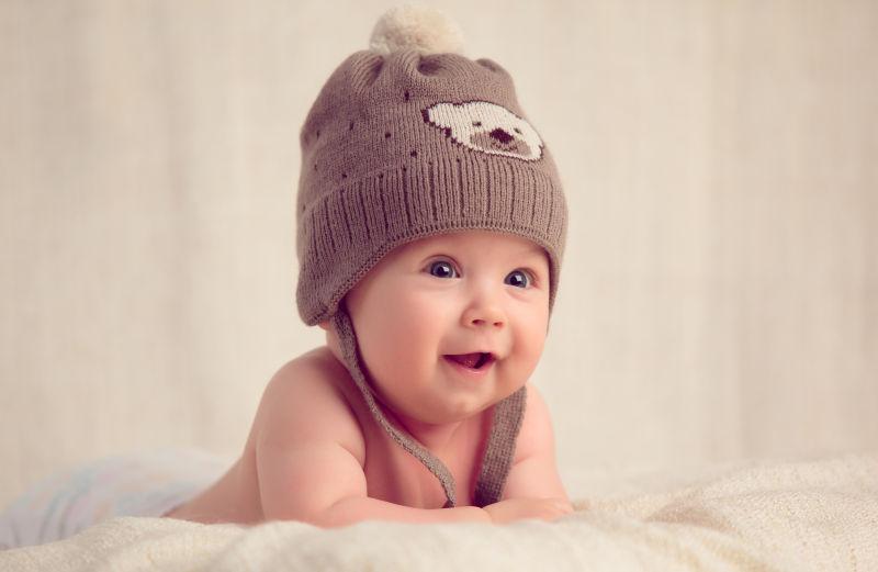 带帽子的婴儿趴在柔软的床罩上