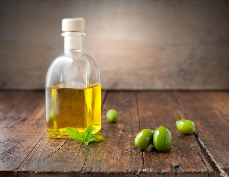 木桌上的橄榄和一瓶橄榄油