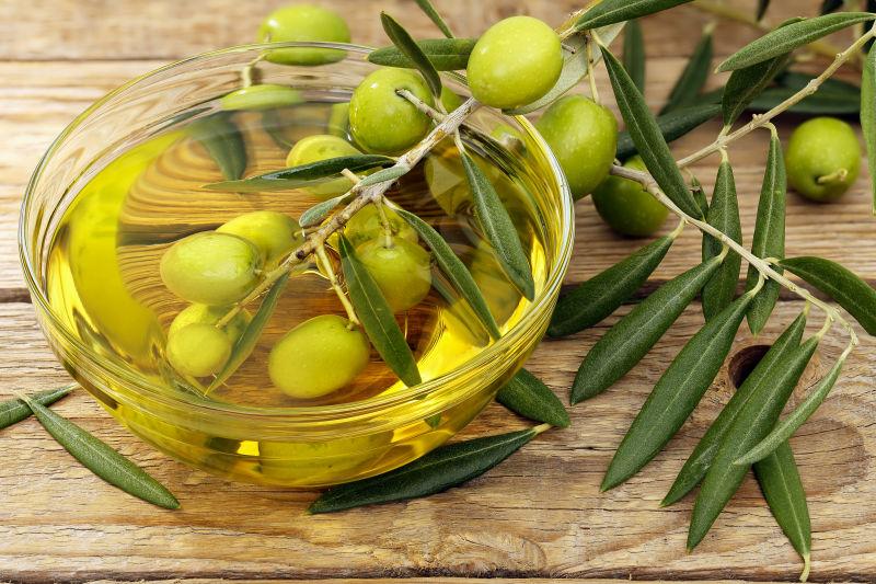 木质桌版上碗中橄榄油浸泡的橄榄