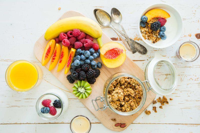 白色木纹理桌上的新鲜水果和浆果酸奶早餐