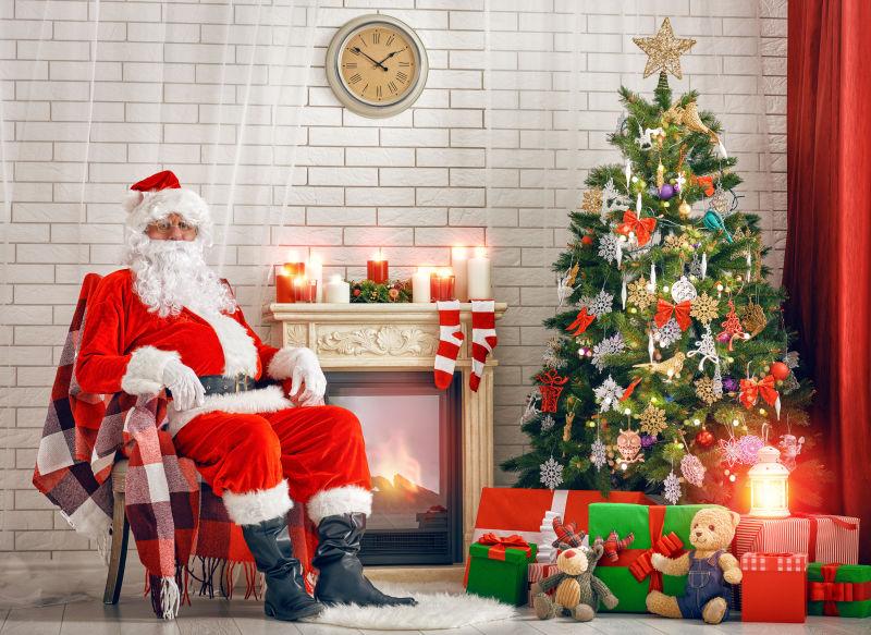 圣诞老人坐在很多礼物的圣诞树旁边