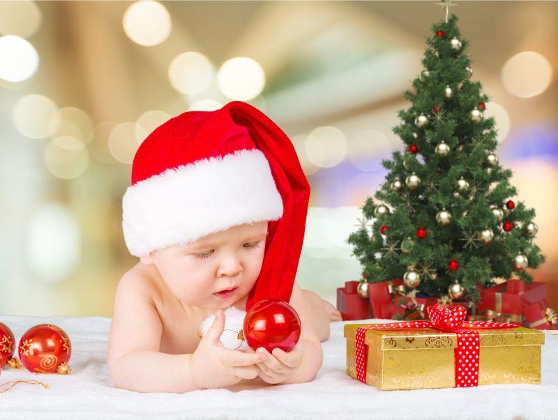 戴着圣诞帽拿着球的婴儿