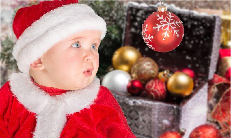 戴着圣诞帽的婴儿看着圣诞小球
