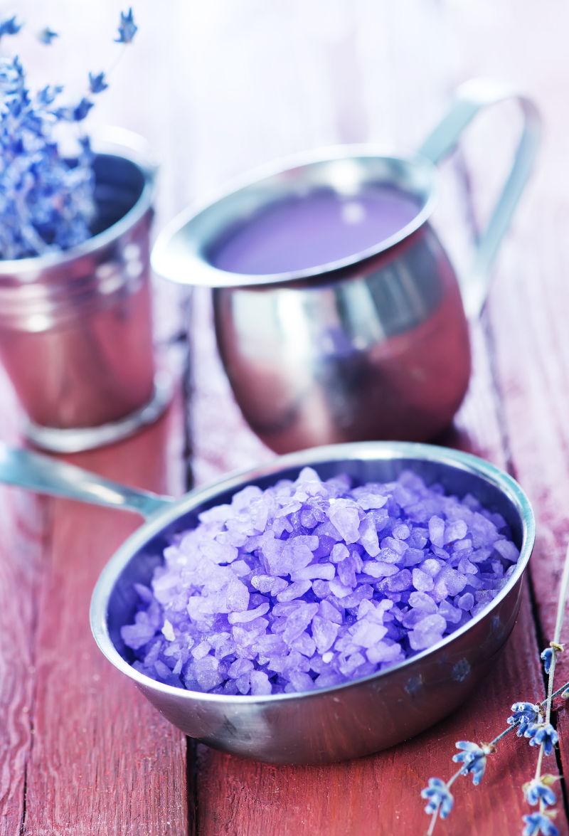 木桌上金属碗里的紫罗兰盐