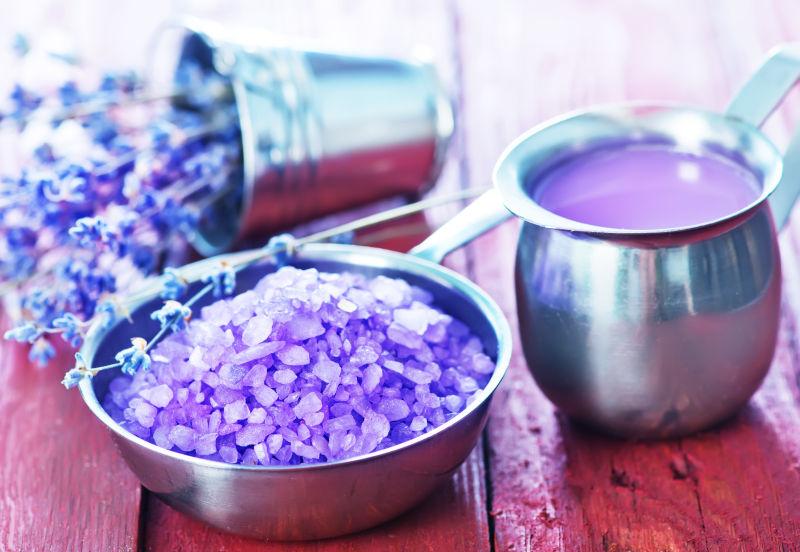 原木桌上金属碗里的紫罗兰浴盐
