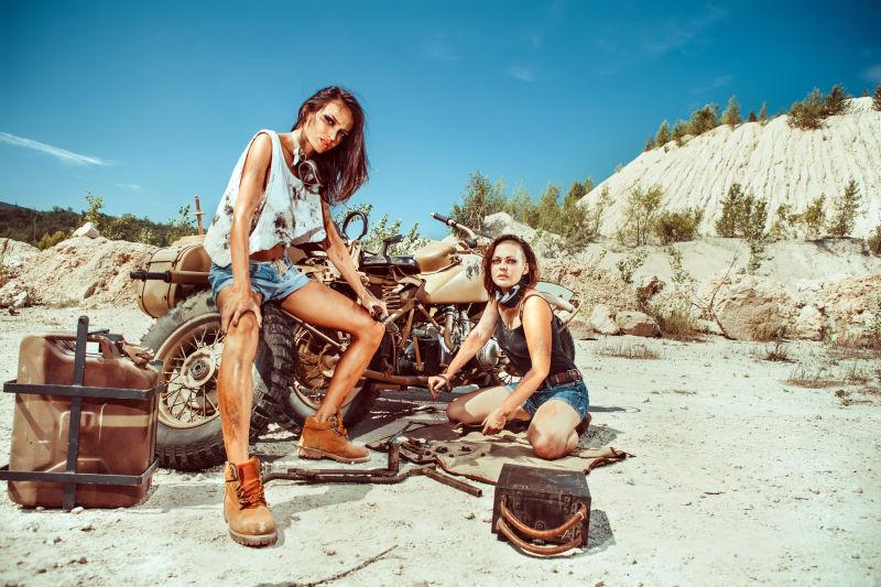 两位性感美女在沙漠上修理旧摩托车