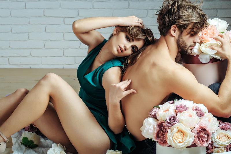 性感的女子靠着抱着花束的男子