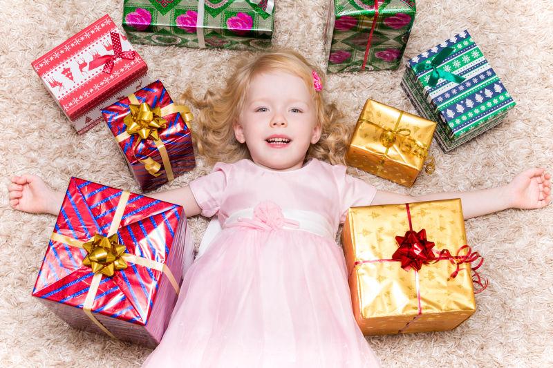 小女孩躺在地上与她的一堆圣诞礼物