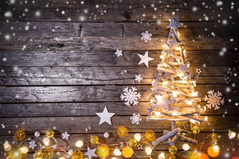 木墙下发光的圣诞树和地上各种圣诞闪光灯泡