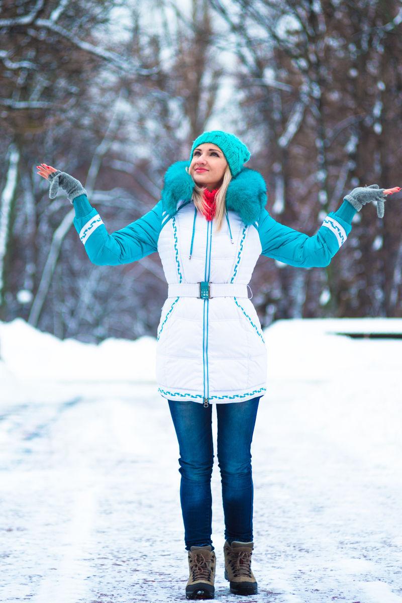 年轻的快乐女人在冬天的城市公园里享受雪