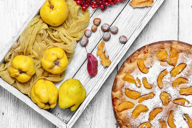 白色木板上的秋木瓜馅饼和黄色水果