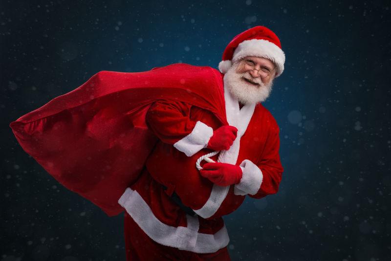 黑色背景下带着红色礼物袋的圣诞老人