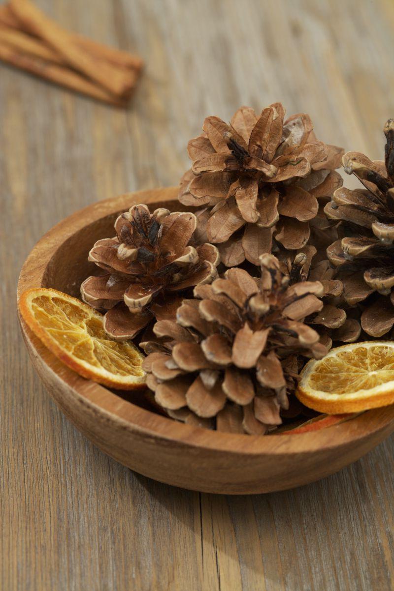 木桌上的木碗里有松果和两片橘子片