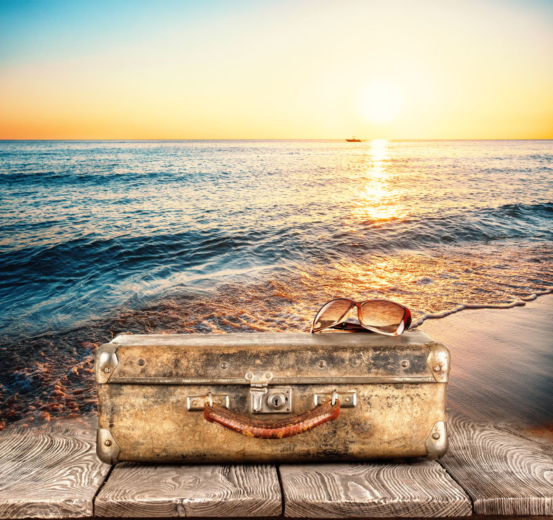 海边日落背景下的手提箱
