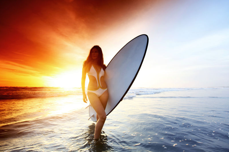 夕阳海滩边的拿冲浪板的美女