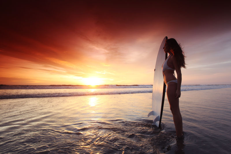 日落时海滩上美丽的冲浪女子