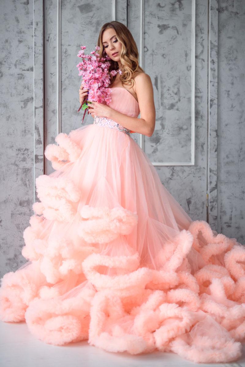 金发模特拿着花束穿着粉色婚纱