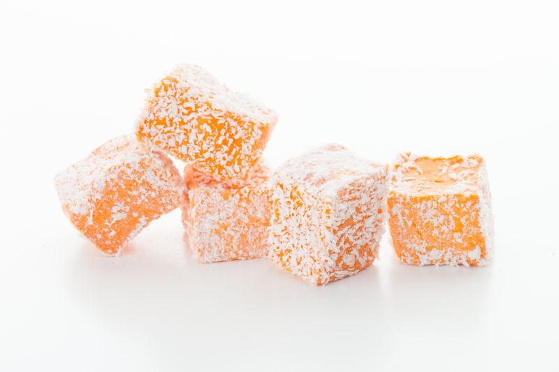 白色背景上的美味的橙色带糖霜的土耳其软糖