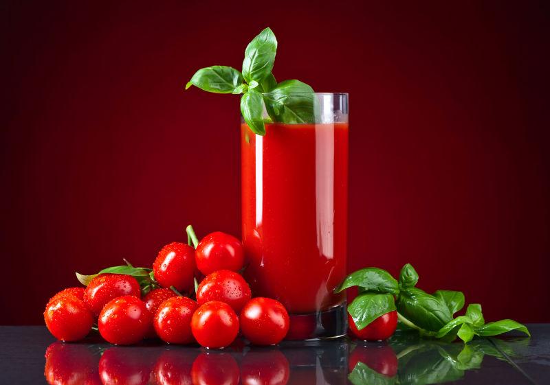 透明杯子里的红色番茄汁和周围的小番茄