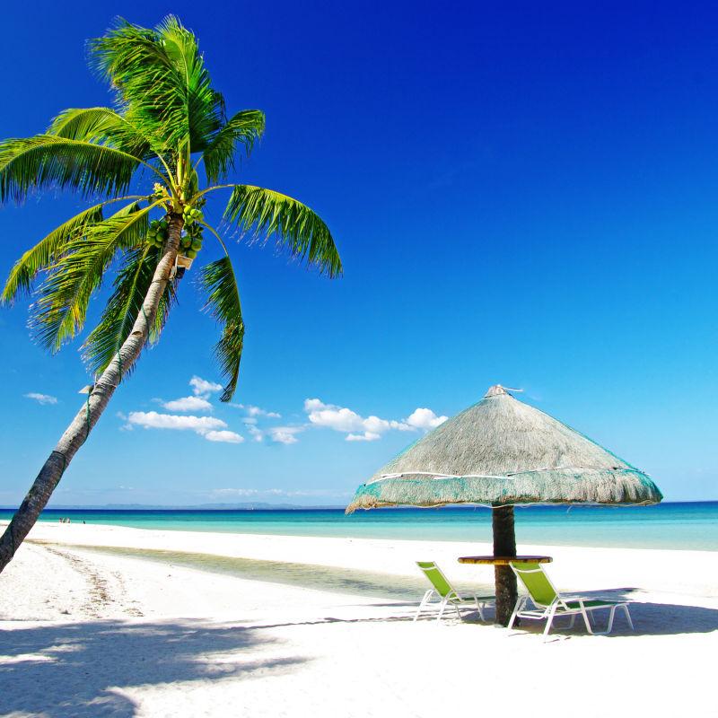 热带白色海滩上的小草棚和休息椅