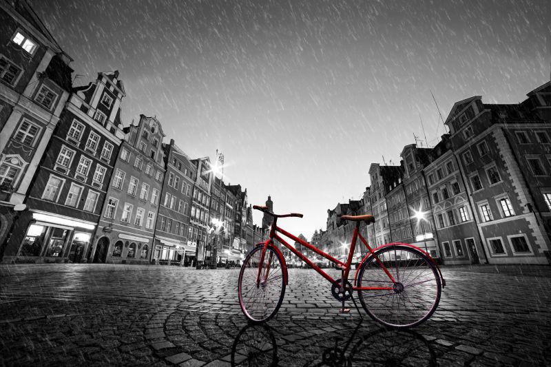 古老的红色自行车在鹅卵石历史悠久的小镇雨中