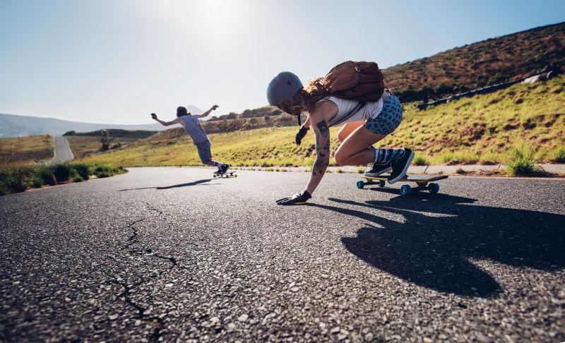 公路上踩着滑板滑行的两个年轻人