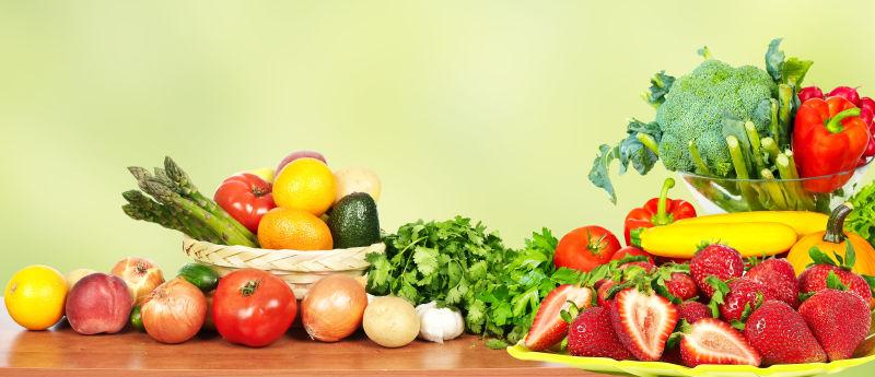绿色背景下木桌上的蔬菜和水果
