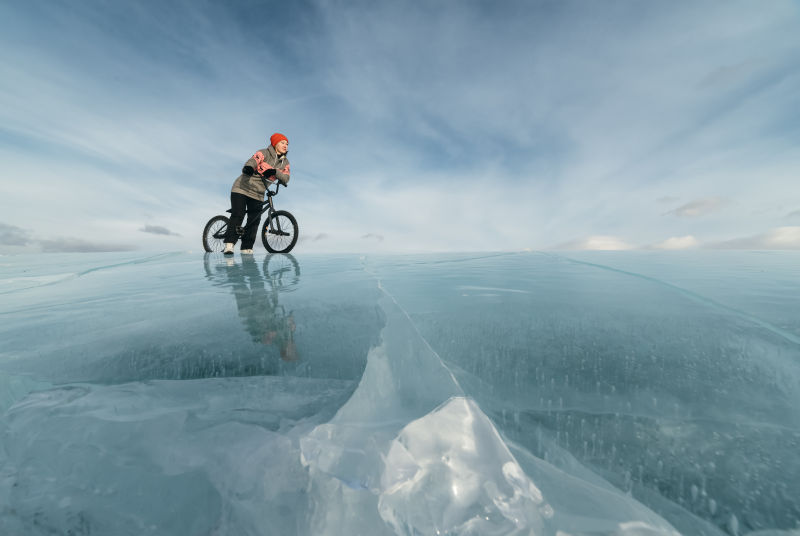 骑自行车站在美丽而危险的冰上的女人