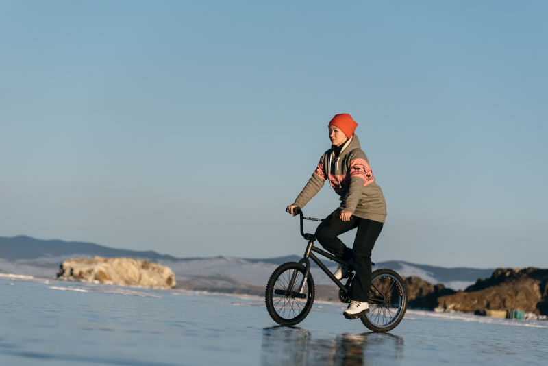 带着红帽子的美女骑着自行车在冰面上