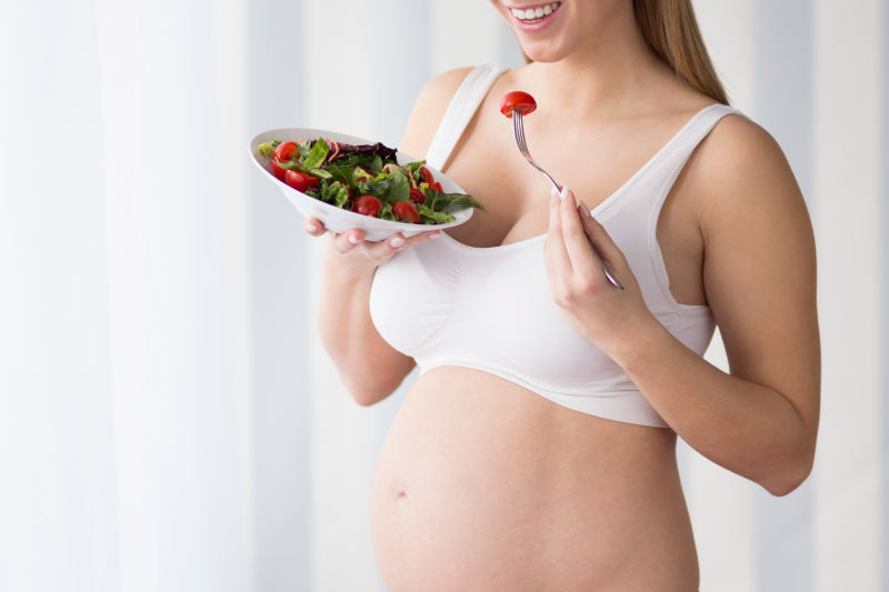 ‎怀孕的妇女吃着蔬菜沙拉