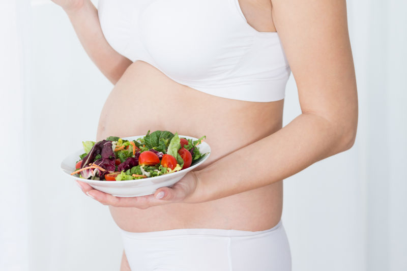 ‎怀孕的妇女手里托着蔬菜
