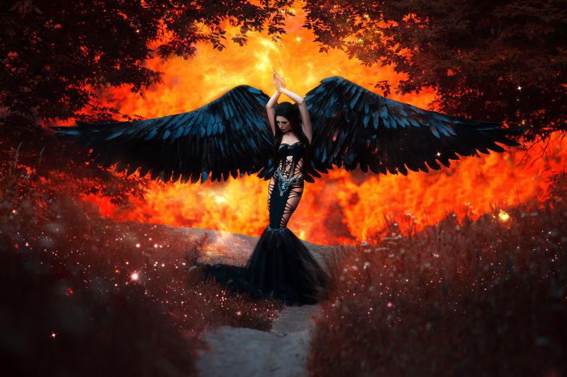 火焰特效背景上拥有黑色翅膀的年轻女人