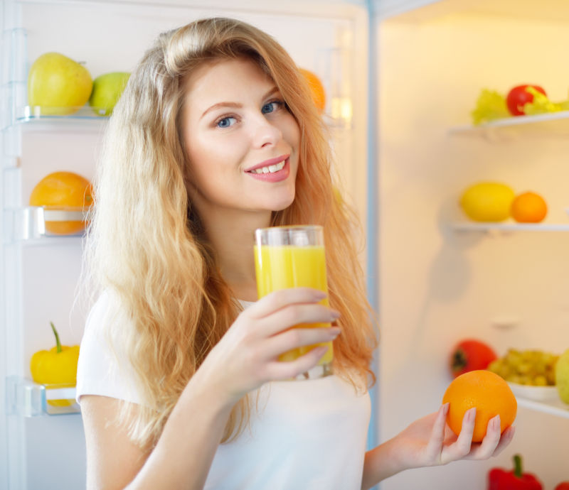 喝着果汁在冰箱拿水果的美女