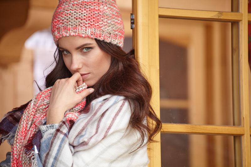 冬季露台上的带红色帽子和围巾的美女