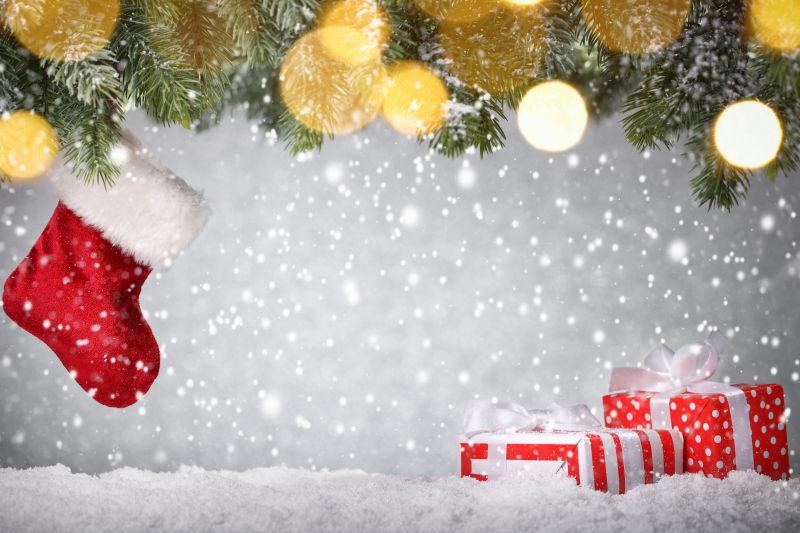 圣诞背景上装饰着圣诞树枝和红色圣诞鞋还有礼物盒