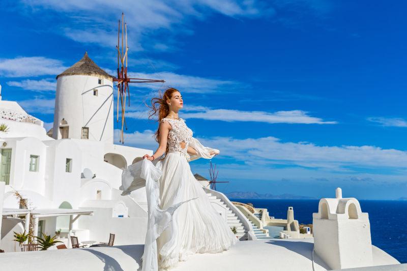 圣托里尼建筑背景下的穿白色长裙的美女