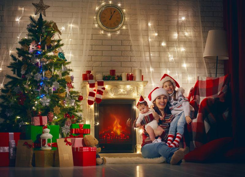 圣诞节的时候年轻的母亲和女儿们坐在壁炉旁