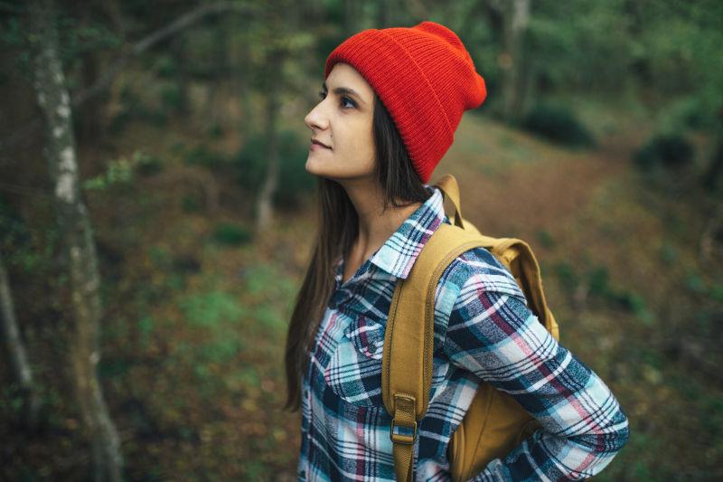 树林里带红帽子的背包女孩
