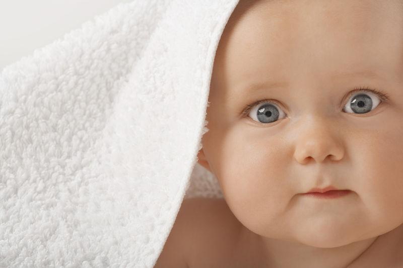 毛巾下蓝色眼睛的可爱宝宝