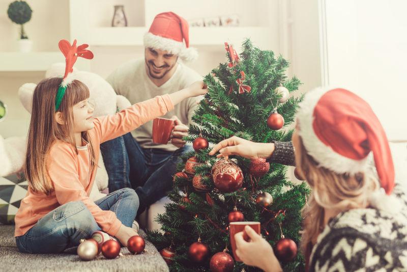 坐在室内装饰圣诞树的家庭