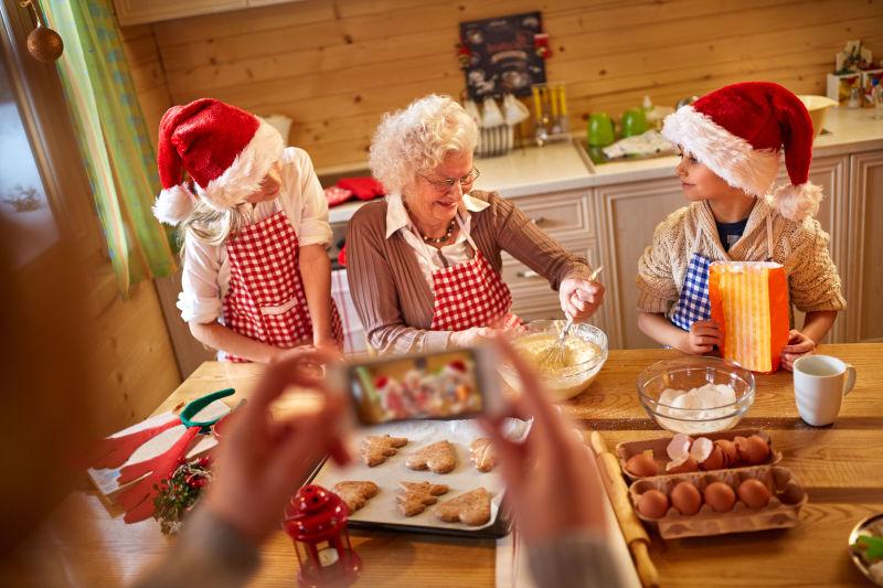 戴着圣诞节帽子和孩子们一起做圣诞节饼干的祖母