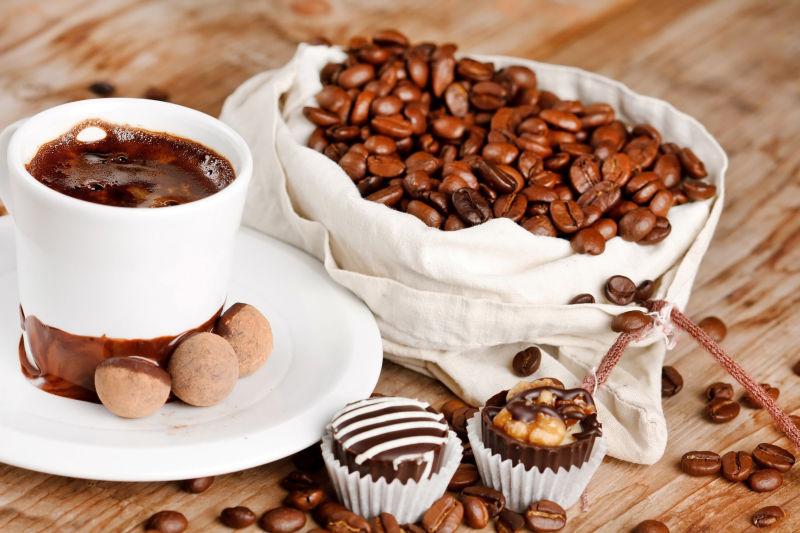 木桌上的咖啡豆和一杯咖啡以及甜点