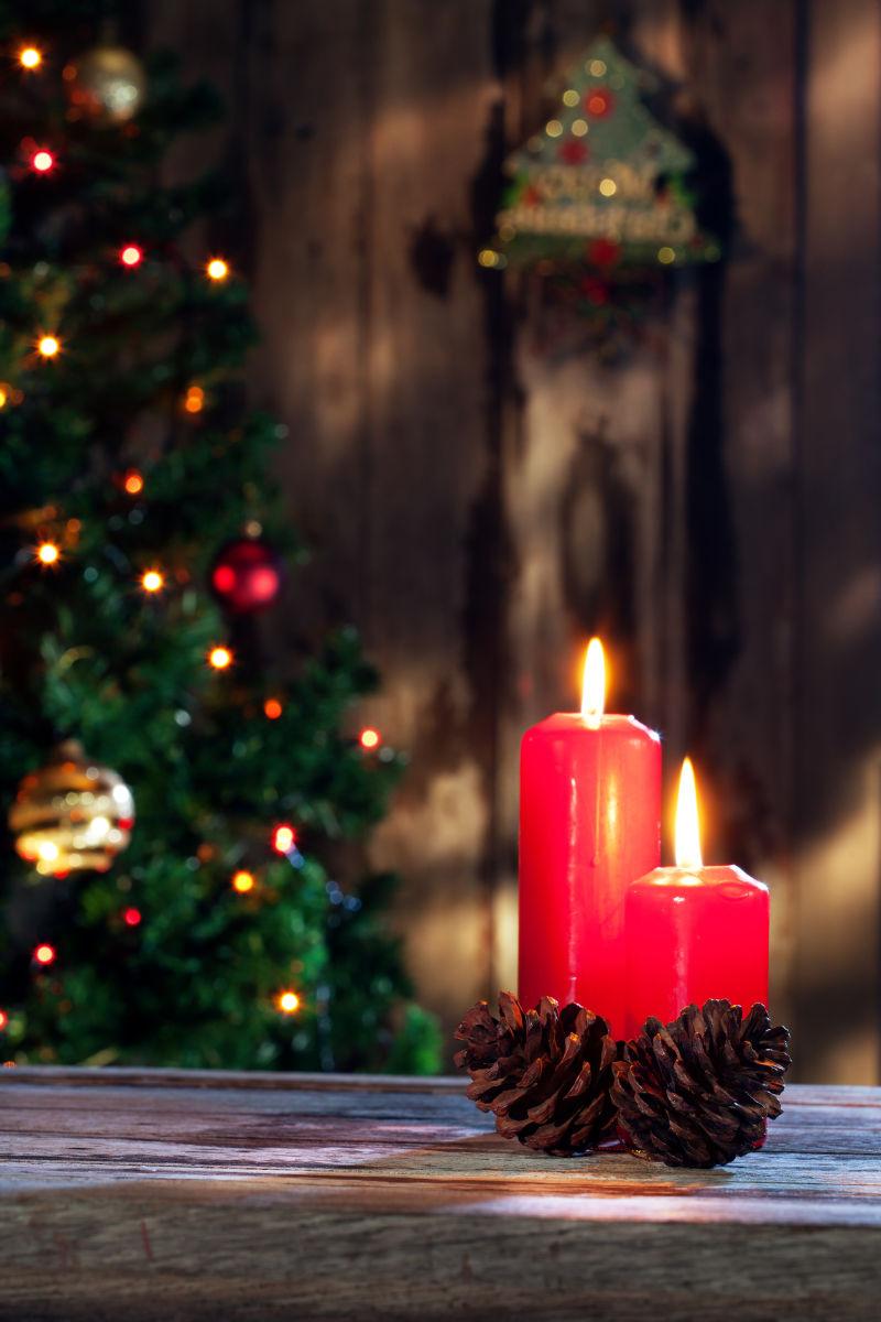 房间里圣诞树盘木桌上有两个点燃的红蜡烛