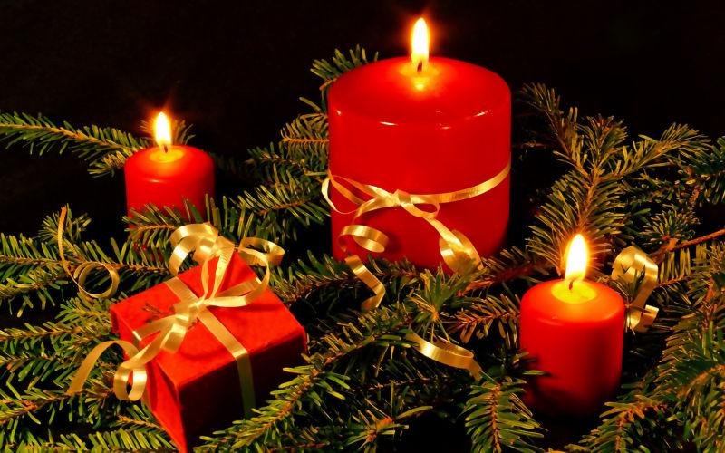 树枝上点燃的三个蜡烛和一个礼物盒