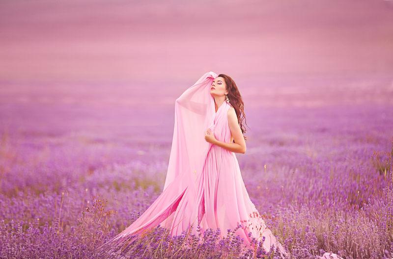 薰衣草园里穿着粉色长裙手扶着额头的美女