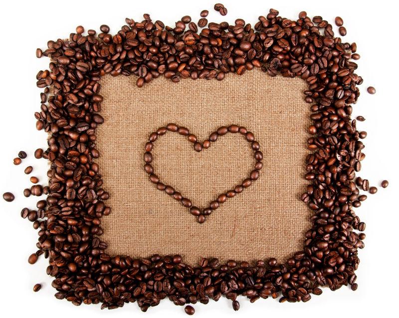 白色背景下的咖啡豆拼成的爱心