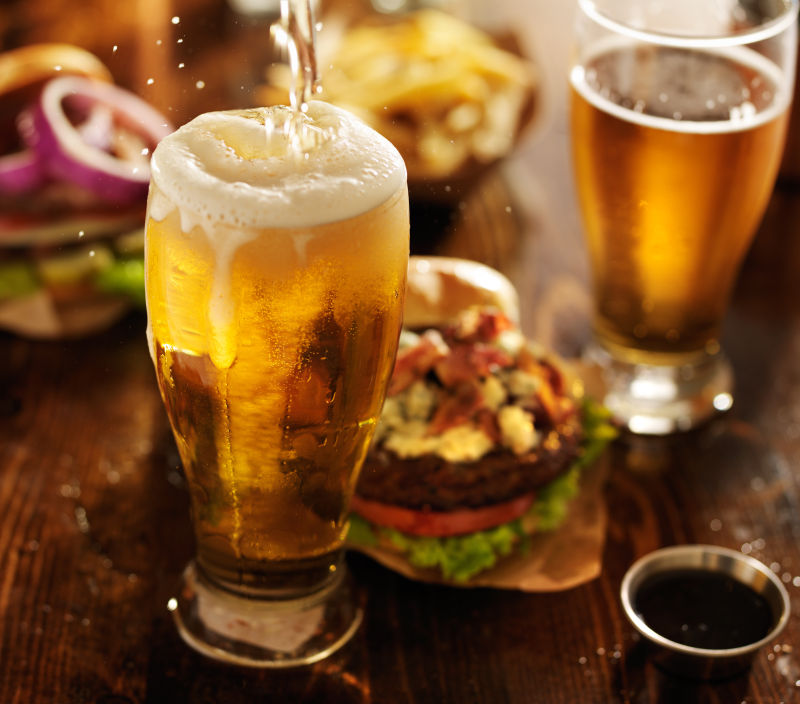 桌上的美食和一杯溢出啤酒泡的啤酒
