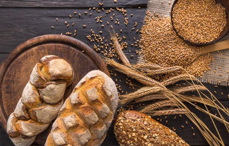 木桌上麻布上的麦粒和旁边的麦穗与小麦面包
