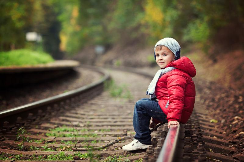 可爱的男孩坐在铁路上