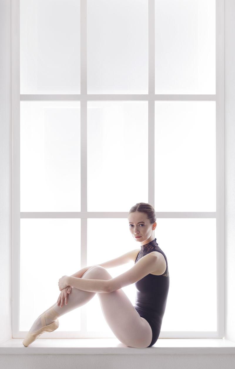 坐在白色窗台上的美女芭蕾舞者